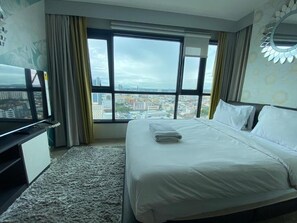 A hotel room with a large bed, a TV, and a view of a cityscape through large windows. - 2 Bed Room Beautiful View Best of Pattaya (Muang Pattaya)