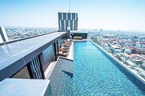 A rooftop infinity pool with a city view, a modern building structure, and a clear sky. - 2 Bed Room Sea View Great Place Central (Muang Pattaya)