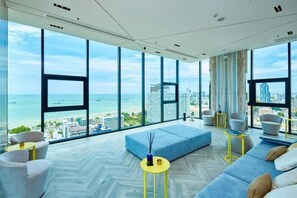 A modern living room with a large window overlooking a cityscape and the sea. - 2 Bed Room Sea View Great Place Central (Muang Pattaya)
