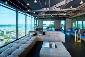 Ein stilvoller Lounge-Bereich mit einer großen Couch, einem Couchtisch und Blick auf die Stadt und das Wasser.