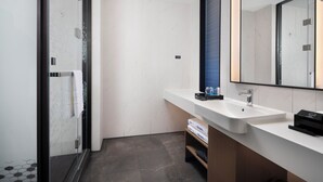 Une salle de bain moderne avec un lavabo blanc, un grand miroir et un espace douche.