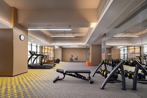 A gym with treadmills, an elliptical, a bench press, and dumbbells. - Hampton by Hilton Fuzhou Software Park (Fuzhou)