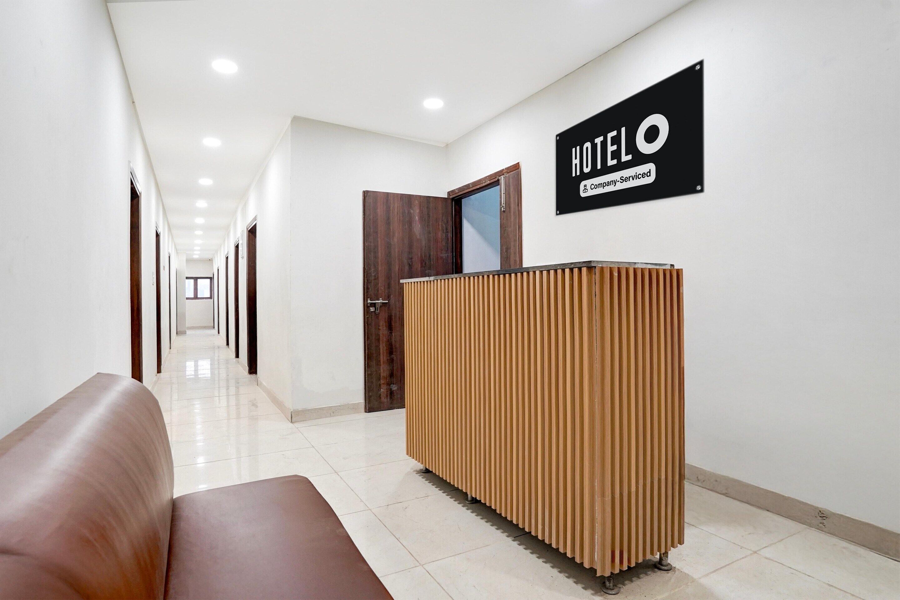 A hotel reception area with a reception desk, a wooden panel wall, and a sign indicating it's company-serviced.