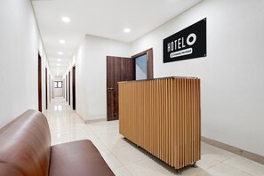 A hotel reception area with a reception desk, a wooden panel wall, and a sign indicating it's company-serviced. - Super Deluxe Room Subhash Nagar Metro Station (New Delhi)