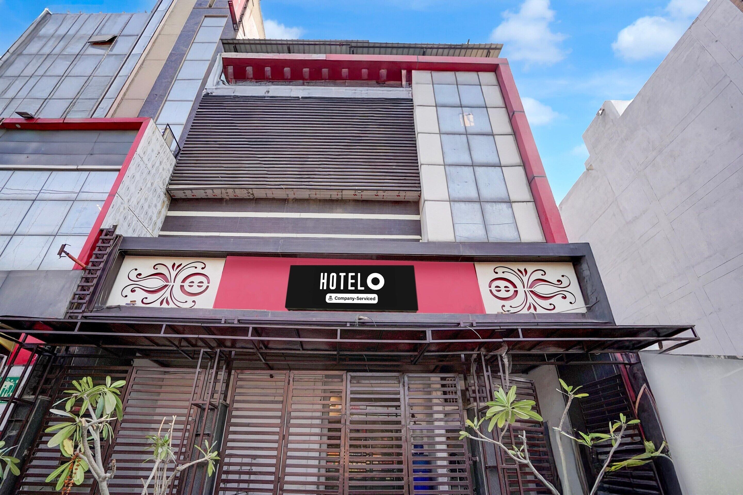 A hotel with a prominent sign, a red and white facade, and metal shutters.