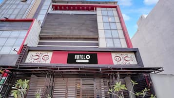 A hotel with a prominent sign, a red and white facade, and metal shutters.