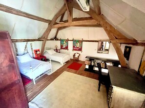 A cozy attic bedroom with a bed, a desk, and a chair. There are two wall-mounted artworks and a mirror. - Half-timbered house with a garden and a pool (Pont-l'Évêque)