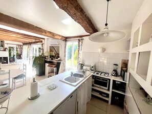 A modern kitchen with a central island, built-in oven, and a dining area with a view. - Half-timbered house with a garden and a pool (Pont-l'Évêque)
