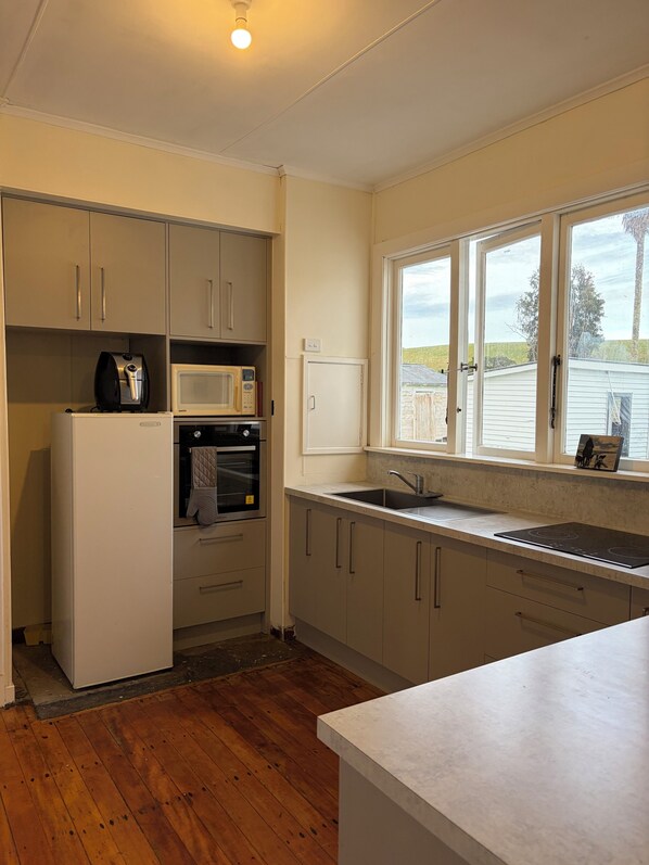 A kitchen with a built-in oven, microwave, and a sink under a window.