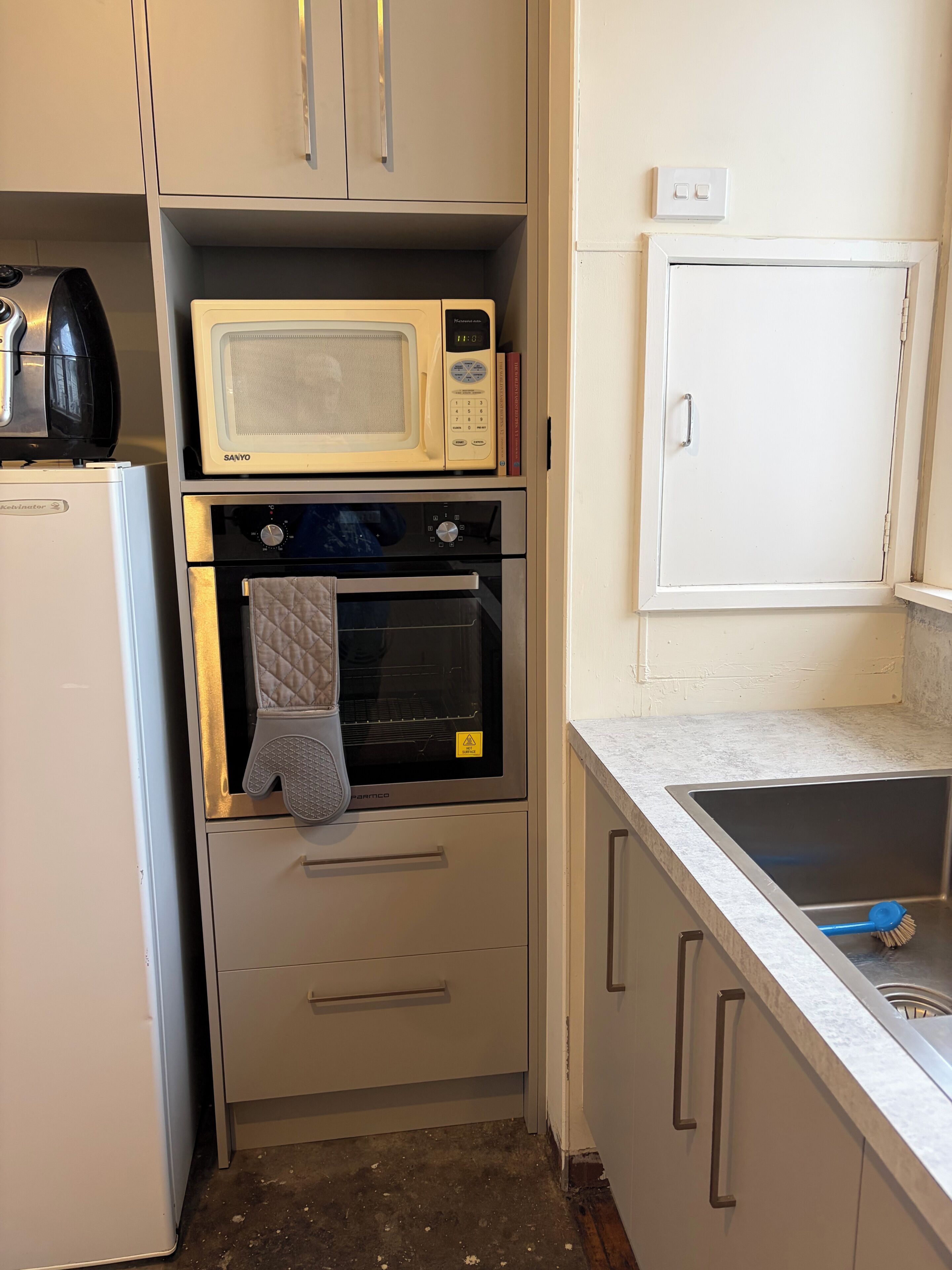 Uma cozinha compacta com micro-ondas, forno e uma pia pequena.