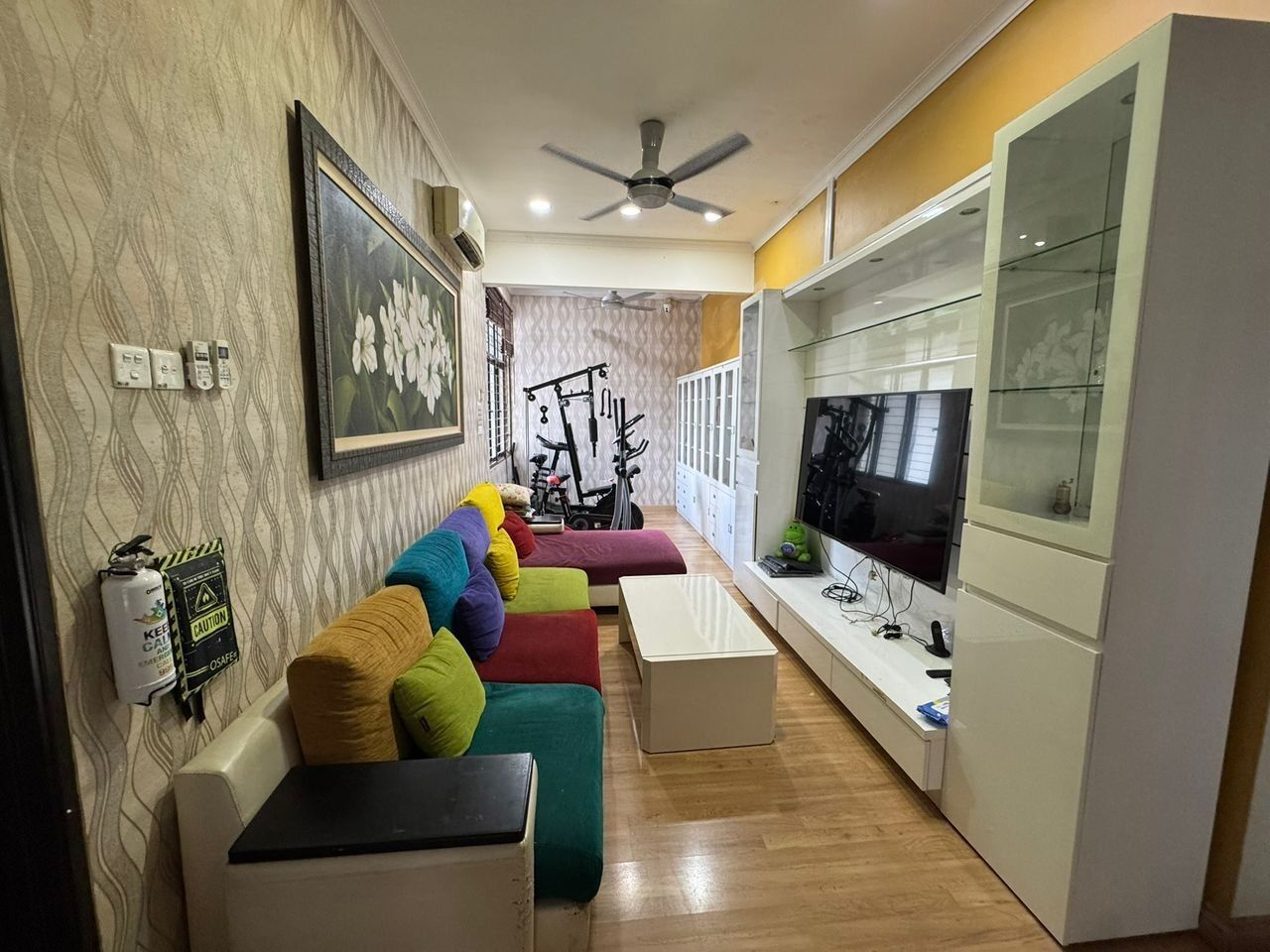 Ein modernes Wohnzimmer mit einer Couch, einem Fernseher und einem Deckenventilator.