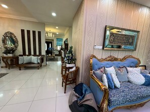 A spacious living area with a blue sofa, wooden chairs, and a dining table. - The Oasis - Modern Villa with Private Pool, Gym, Pond & Chef’s Kitchen (Bandar Baru Bangi)