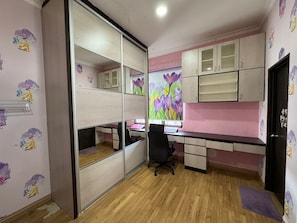 A room with a desk, a chair, a wardrobe, and a door.