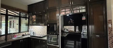 Una cocina con alacenas de madera oscura, un refrigerador de acero inoxidable y un salpicadero de azulejos.