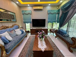 A living room with a sofa, a coffee table, a TV, and a decorative vase. - The Oasis - Modern Villa with Private Pool, Gym, Pond & Chef’s Kitchen (Bandar Baru Bangi)