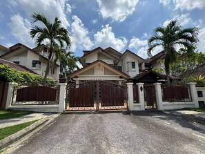 A gated residential area with multiple houses, a central gate, and palm trees.