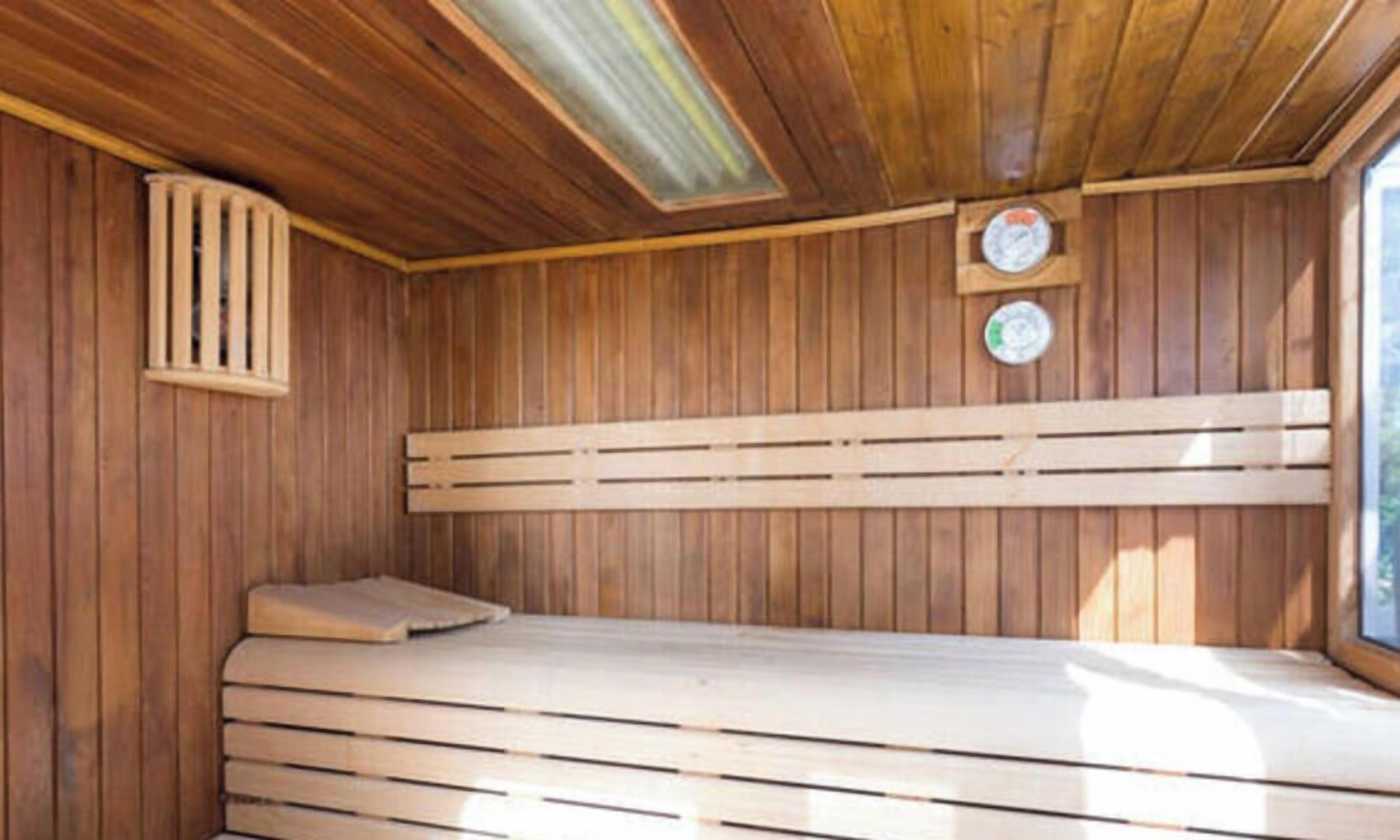 Un sauna en bois avec un banc, un plafond à lattes et deux horloges fixées au mur.