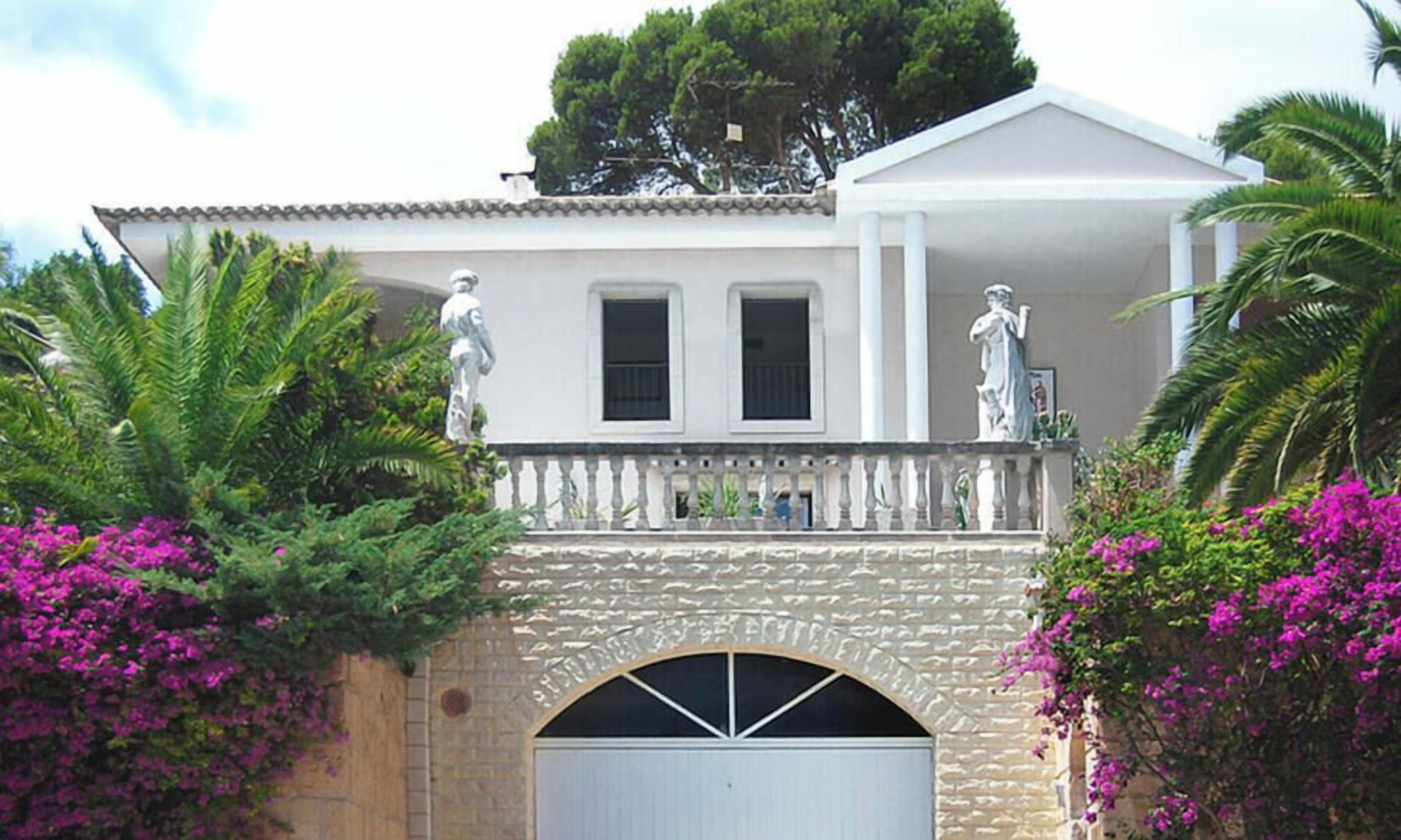 Un bâtiment doté d’une arche en pierre, de deux statues et d’une porte de garage blanche.