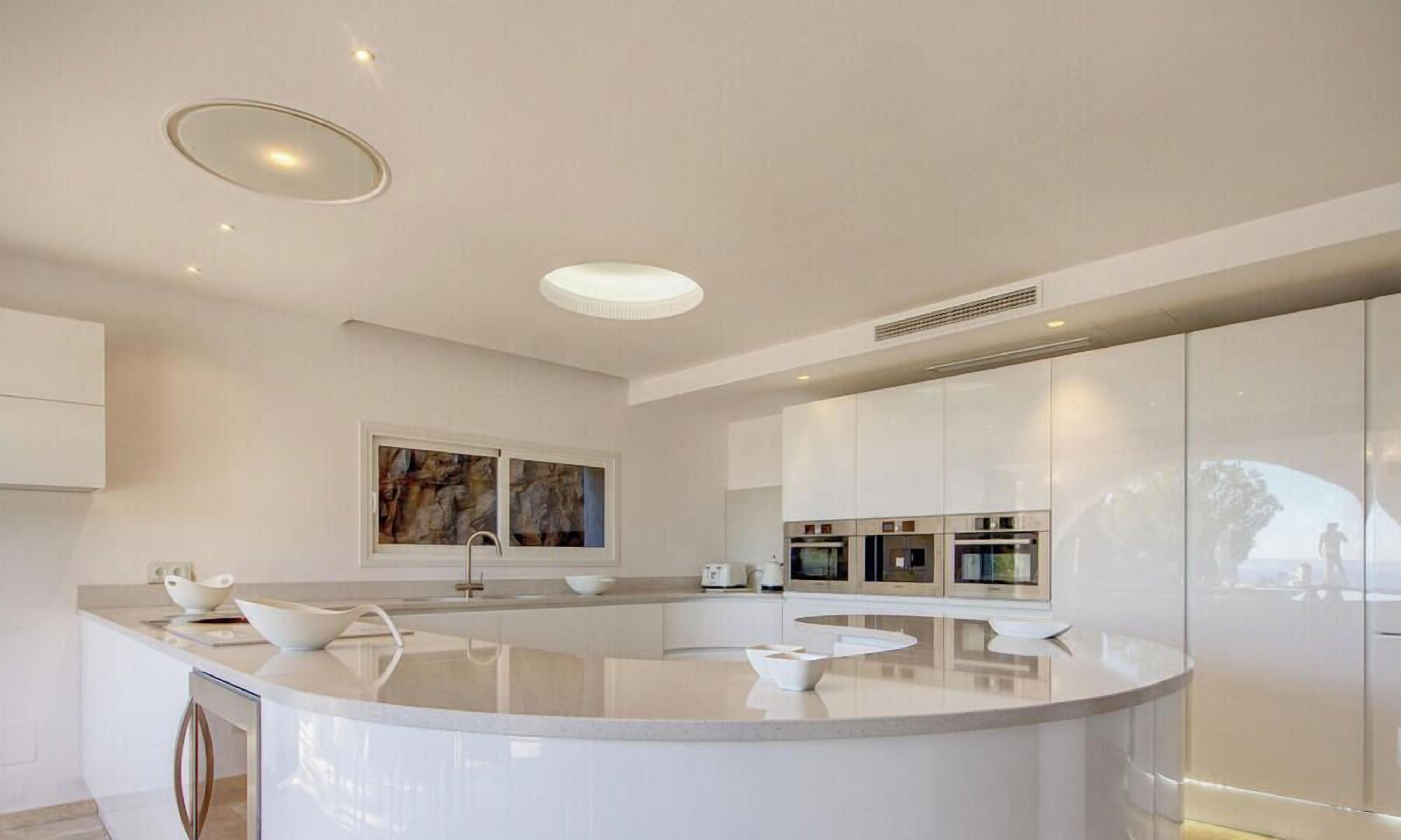 A modern kitchen with a central island, built-in appliances, and a recessed ceiling light.