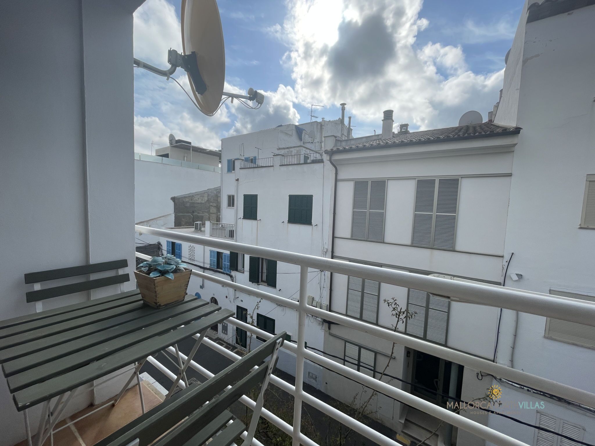 Uma varanda com uma mesa, um vaso de planta e uma antena parabólica.