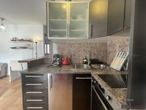 A modern kitchen with a built-in dishwasher, a coffee maker, and a kettle on the countertop. - Apartment  by Interhome (Port Pollença)