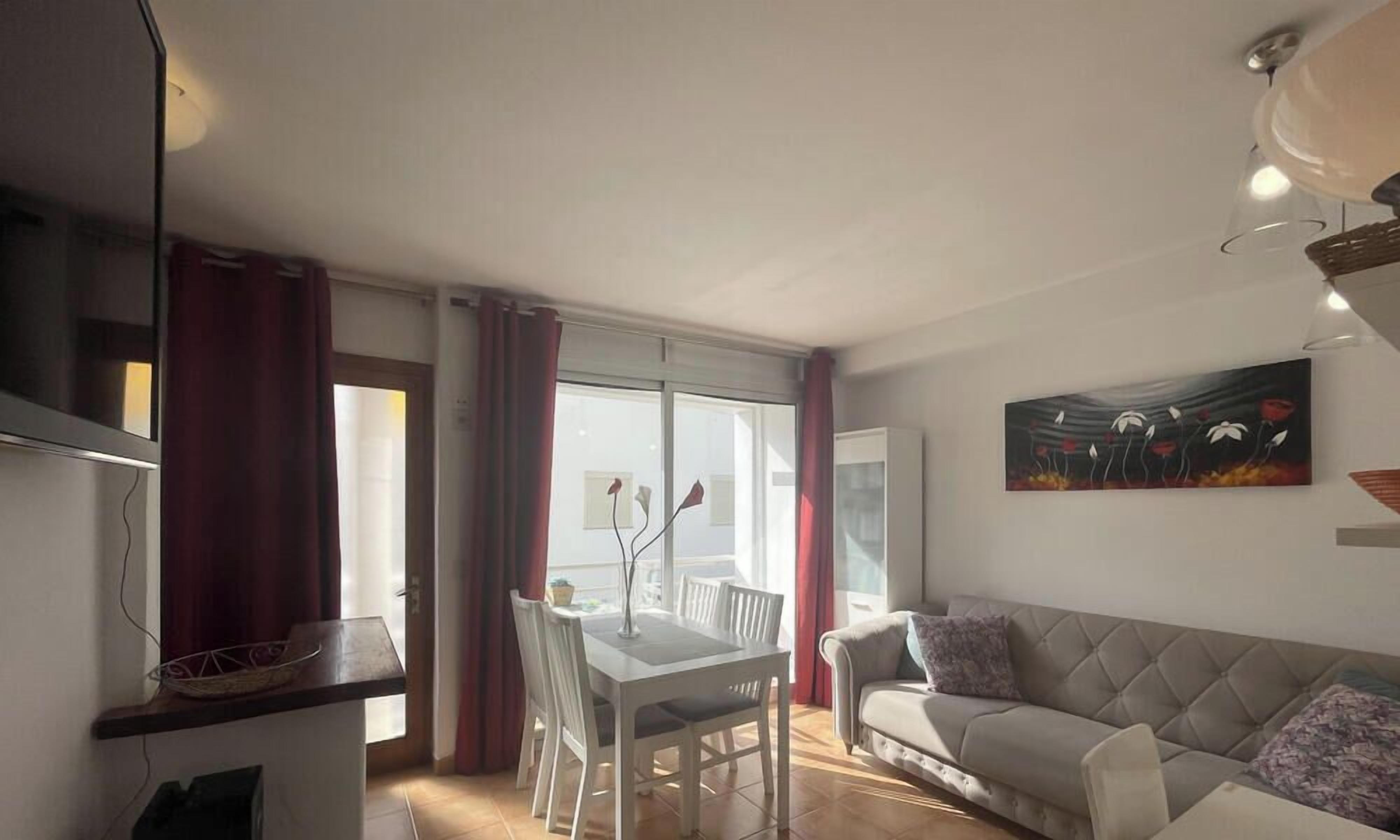A living room with a sofa, a dining table with chairs, and a painting on the wall.