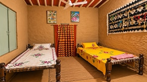 A room with two wooden beds, a ceiling fan, and a patterned wall hanging.