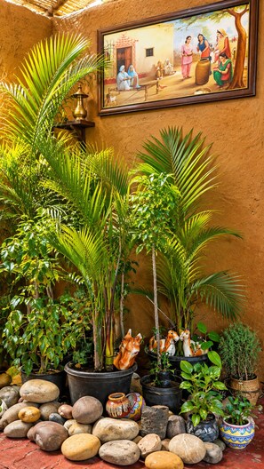 Una habitación con una pared rústica, un cuadro enmarco y una variedad de macetas con plantas y piedras.