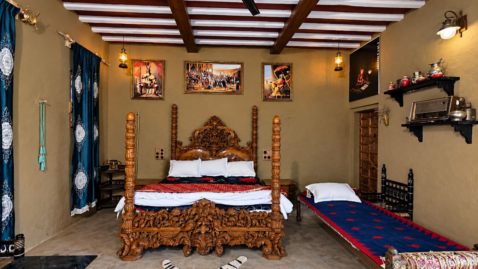 Una cama con dosel tradicional y tallas ornamentales, una cama individual con cubrecama estampado, y una estantería con utensilios de cocina.