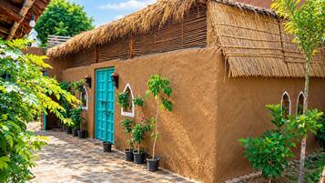 Uma casa tradicional com telhado de palha, porta azul e vasos de plantas ao longo do caminho.
