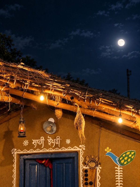 A traditional building with a thatched roof, a blue door, and a peacock decoration.