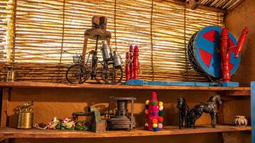 Interior rústico com prateleiras exibindo diversos objetos, incluindo uma bicicleta, recipientes de metal e itens decorativos.