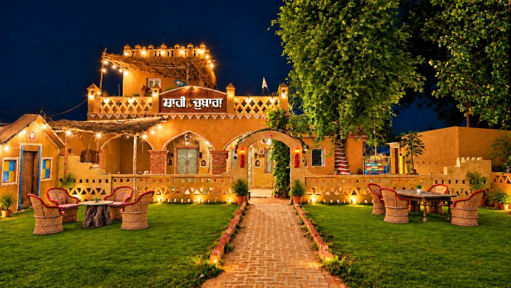 A traditional building with a central archway, surrounded by a well-lit garden and outdoor seating area.