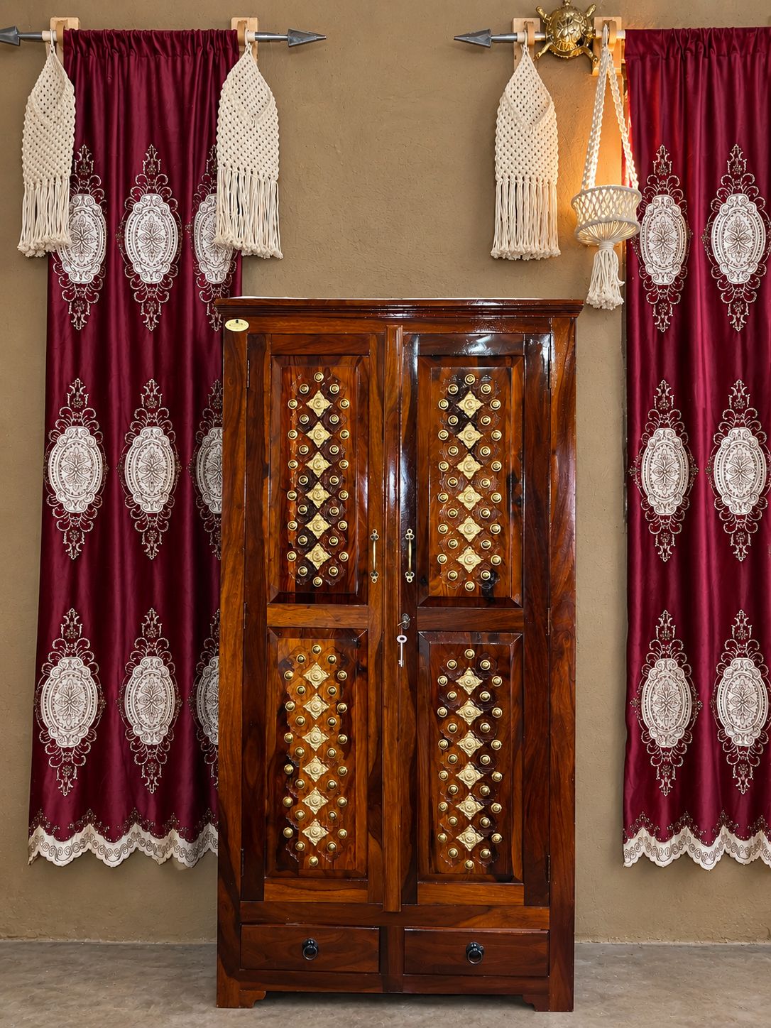 Un armadio in legno con elaborate decorazioni a motivo di diamanti e un completo di tende abbinate con frange.