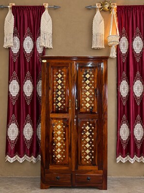 Un armario de madera con intrincados diseños de diamantes y un juego de cortinas a juego con flecos.