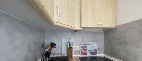 A compact kitchen with wooden cabinets, a sink, and a coffee maker.