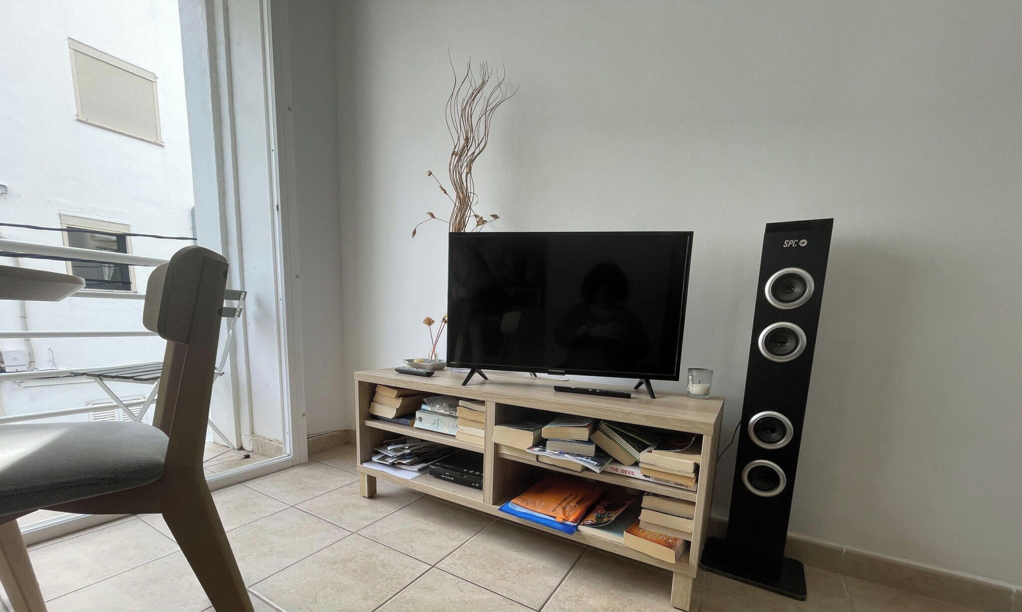 Un salon équipé d’un téléviseur à écran plat, d’un meuble de rangement en bois et d’une grande enceinte.