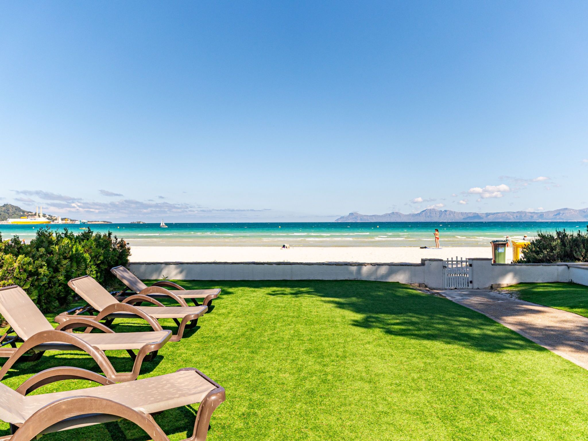 Vista de una playa con sillas de descanso y una zona cubierta de césped.