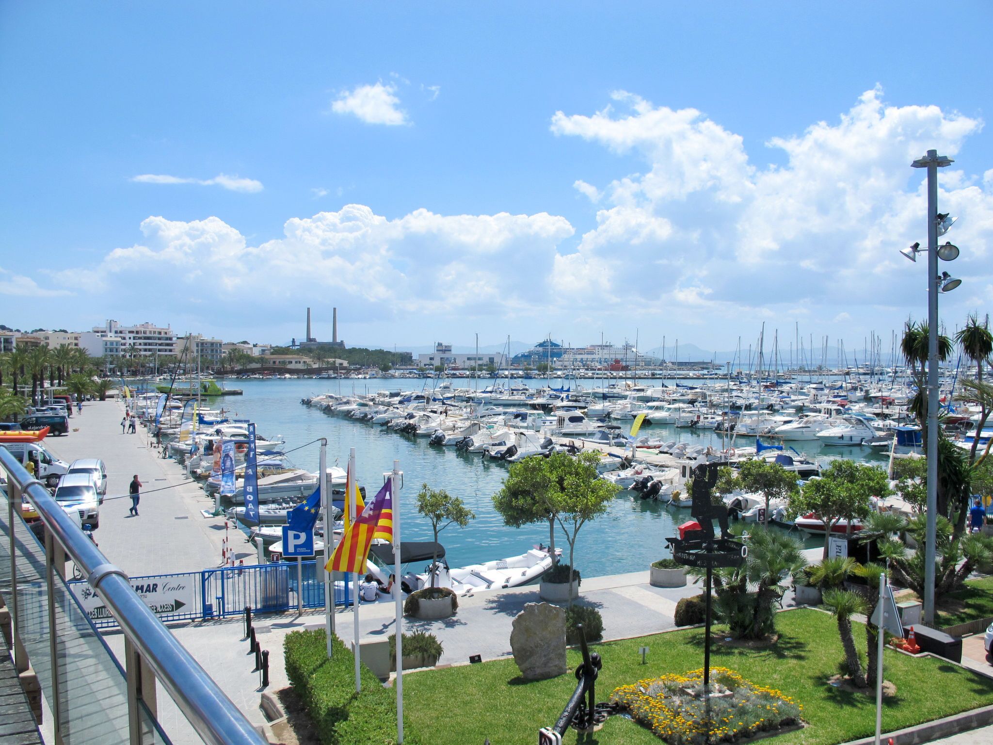 A marina with numerous boats docked, a clear sky, and a cityscape in the background.