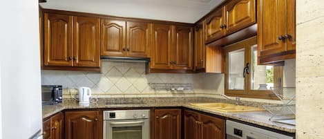 A kitchen with wooden cabinets, a stainless steel oven, a dishwasher, and a granite countertop.