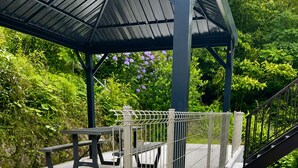 A covered outdoor area with a picnic table and a metal fence.