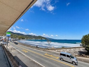 A coastal road with a view of the sea, a pedestrian path, and a FamilyMart store.