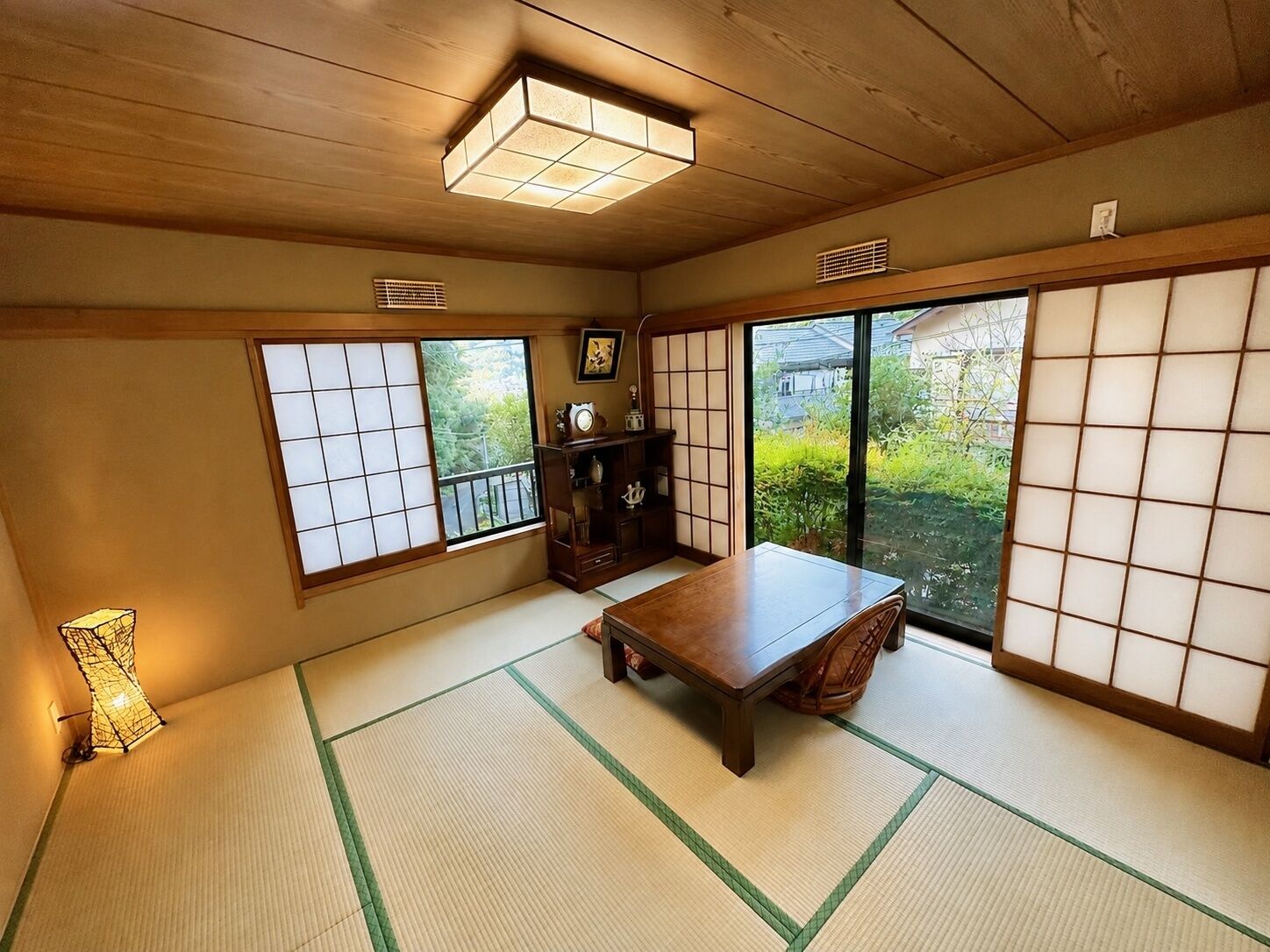 A traditional Japanese room with tatami flooring, a wooden table, and sliding doors.