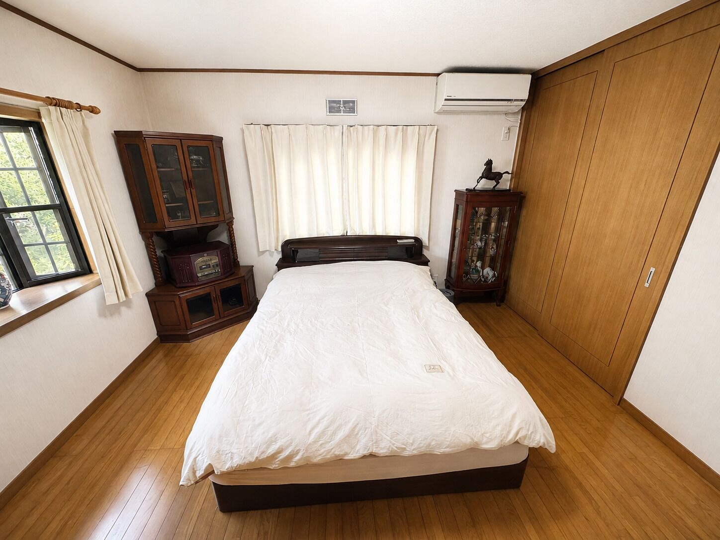 Una camera da letto con un letto, un'armadio in legno e una finestra con tende.