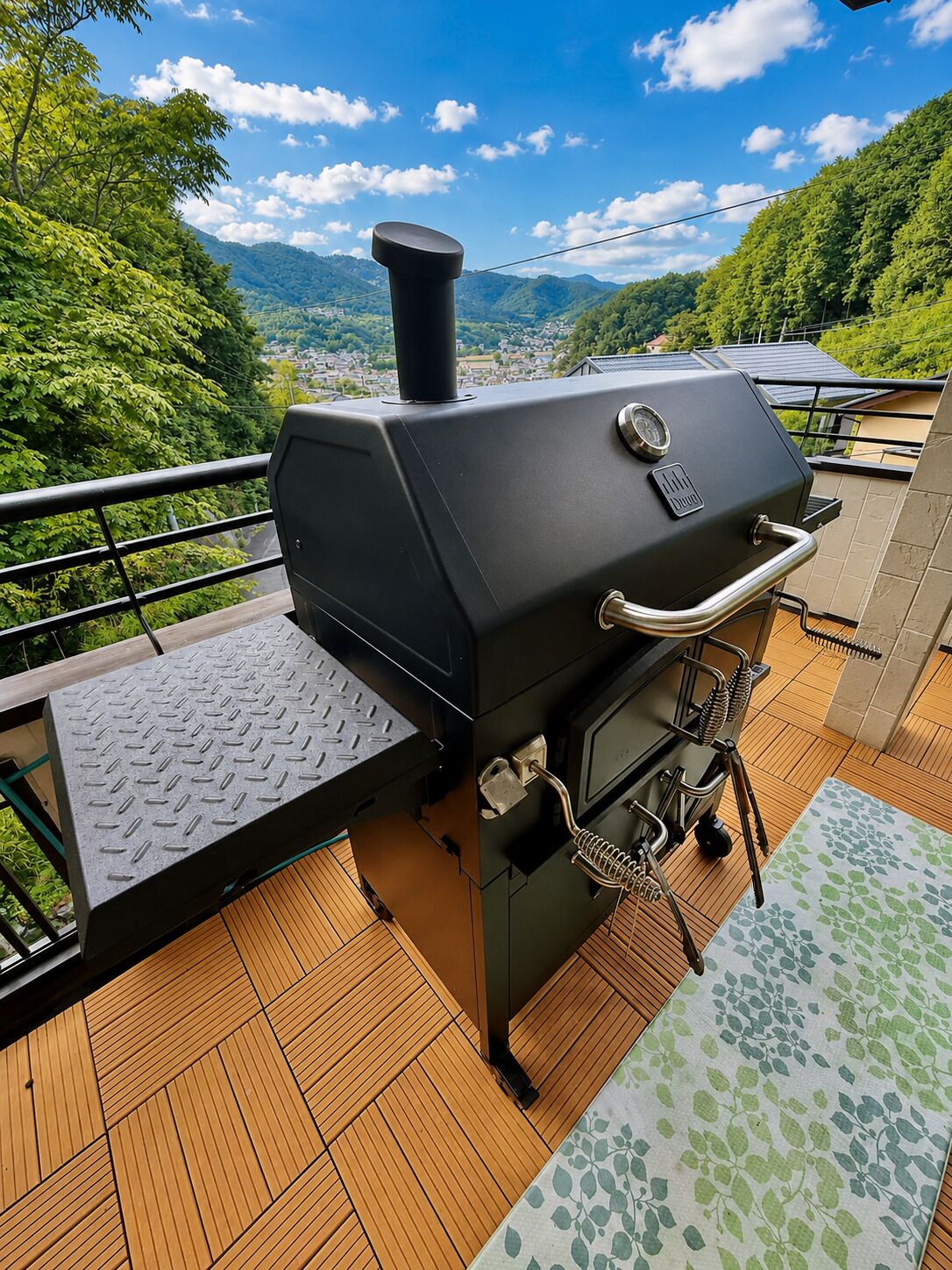A barbecue grill on an outdoor deck with a view of a mountainous landscape.