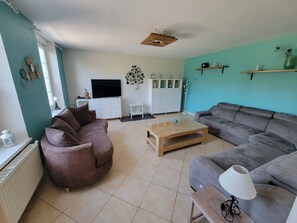 A living room with a brown sofa, a grey sofa, a wooden coffee table, and a TV on a white cabinet.