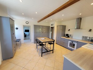 A modern kitchen with grey cabinets, a wooden dining table, and a built-in oven. - Large vacation rental for 10 people with a sauna, garden, and fireplace (Anor)