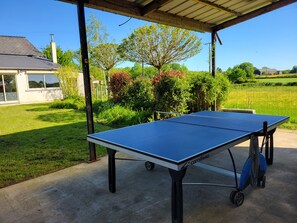 A table tennis table with a cart, set up outdoors under a shelter. - Large vacation rental for 10 people with a sauna, garden, and fireplace (Anor)