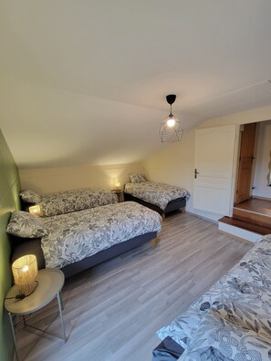 A bedroom with a bed, bedside lamps, a small table, and a staircase leading to an upper level. - Large vacation rental for 10 people with a sauna, garden, and fireplace (Anor)