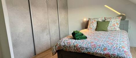 Un dormitorio con una cama, una mesita de noche, una lámpara y un armario.